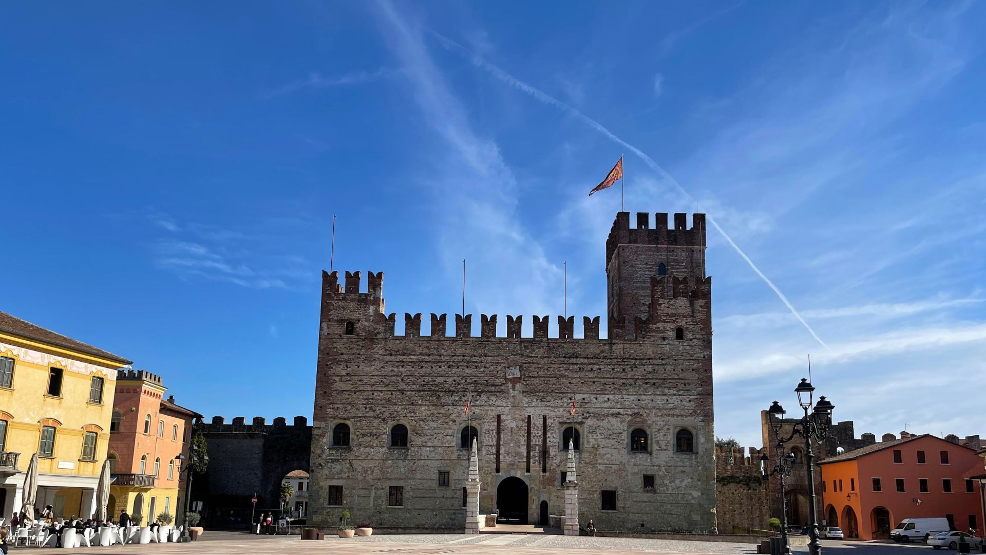 Visite guidate provincia di Vicenza. Castello medievale in piazza con bandiera e cielo sereno.